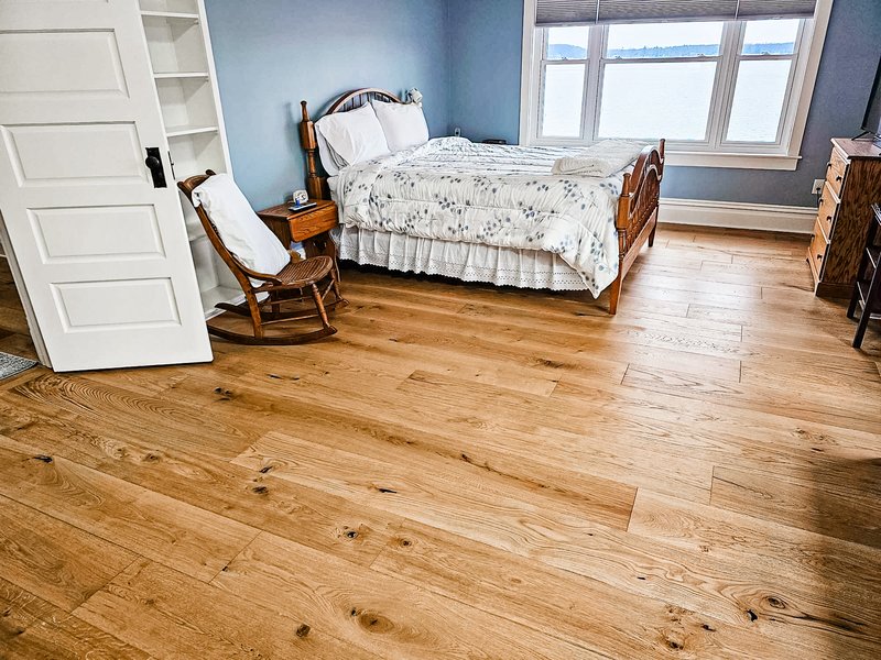 Warm hardwood flooring in a bright bedroom by Absolute Floor Covering